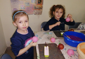 Dziewczynki siedzą przy stoliku i ozdabiają bombki